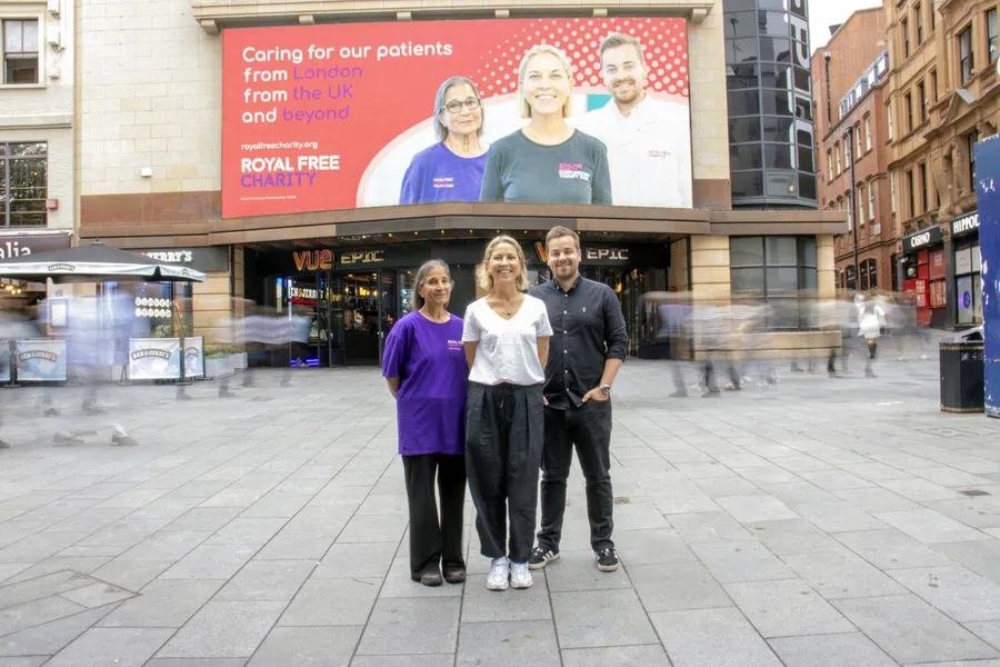 George with two colleagues in Leicester Square, in front of the Royal Free Charity campaign screen